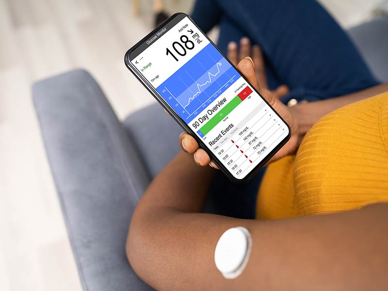 Continuous glucose monitor on arm and phone showing result
